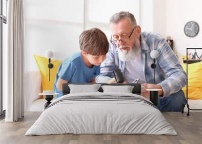 Grandfather teaching little boy to repair clock at home Wall mural