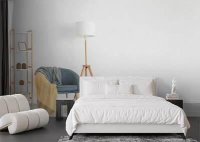 grey armchair with plaid, table and shelving unit near light wall Wall mural