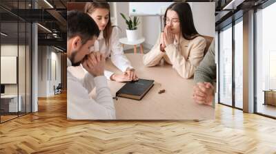 Group of business people praying with Holy Bible at table in office Wall mural