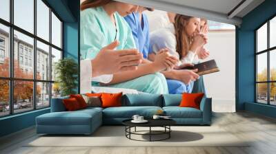 Group of doctors praying with Holy Bible in clinic, closeup Wall mural