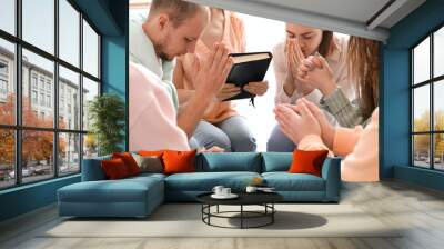 Group of people praying with Holy Bible in room Wall mural