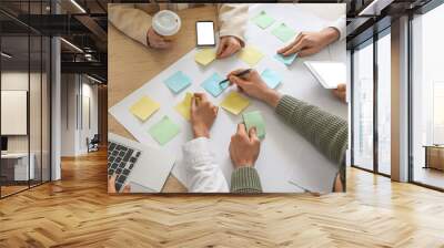 Group of people with sticky notes working on business plan at table in office, closeup Wall mural