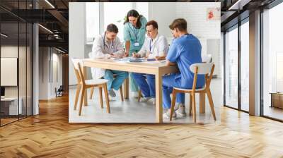 Group of young doctors working at table in clinic Wall mural