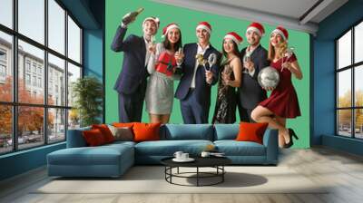 Group of young people in Santa hats with champagne and figure 2024 on green background. New Year celebration Wall mural