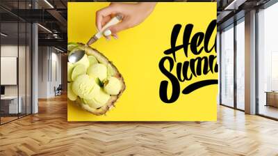 Hand of woman eating tasty pineapple ice cream and text HELLO, SUMMER on yellow background Wall mural