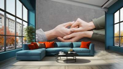 Hands of woman comforting young man on grey background Wall mural