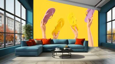 Hands with flip-flops on yellow background Wall mural