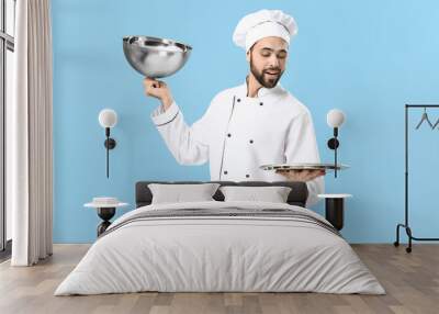 Handsome male chef with empty tray on color background Wall mural