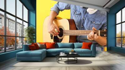 Handsome man playing guitar on color background Wall mural