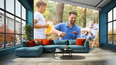 Handsome man putting grilled meat on plate at barbecue party Wall mural