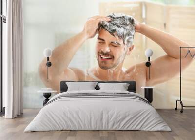 Handsome man washing hair at home Wall mural