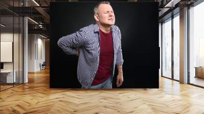 Handsome middle-aged man suffering from back pain on dark background Wall mural