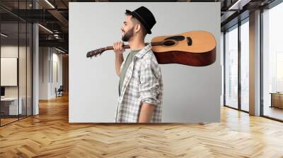 Handsome musician with guitar on light background Wall mural