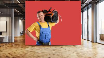 Handsome plumber with tools bag on color background Wall mural