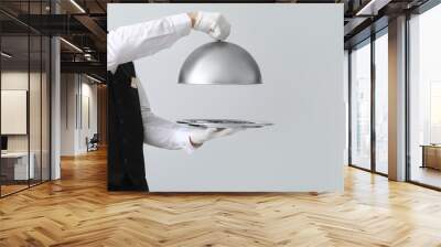 Handsome waiter with tray and cloche on light background Wall mural