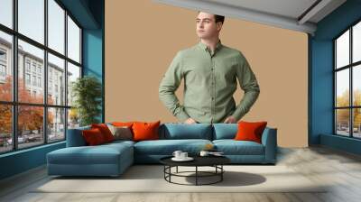 Handsome young man in stylish green collar shirt on brown background Wall mural