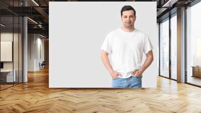 Handsome young man in stylish t-shirt on light background Wall mural