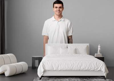 Handsome young man in stylish white t-shirt on grey background Wall mural