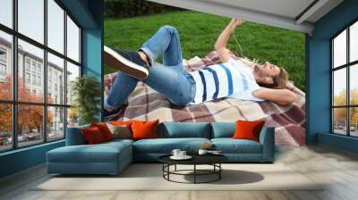 Handsome young man listening to music in park Wall mural