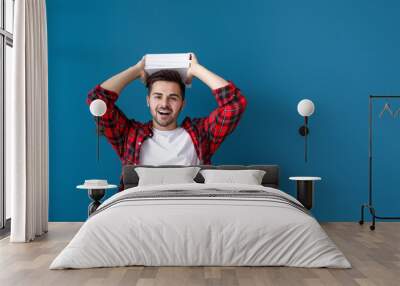 Handsome young man with books on color background Wall mural