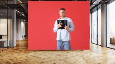 Handsome young man with Holy Bible on red background Wall mural