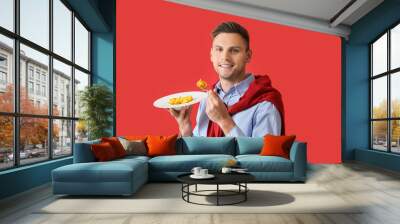 Handsome young man with plate of tasty ravioli on color background Wall mural