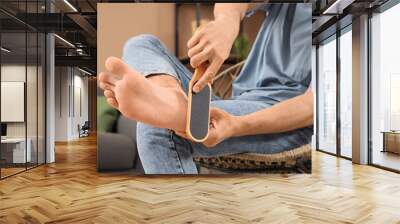 Handsome young man with pumice doing pedicure at home, closeup Wall mural