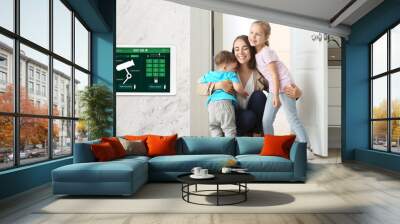 Happy children and their mother in hall under protection of smart home security system Wall mural