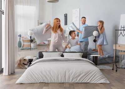 Happy family fighting on pillows in bedroom at home Wall mural