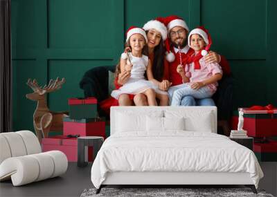 Happy family in Santa hats with Christmas gifts near green wall Wall mural