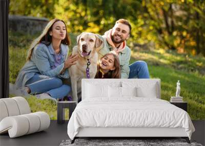 Happy family with Labrador dog sitting on plaid in park Wall mural