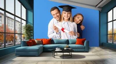 Happy female graduation student with her parents on color background Wall mural