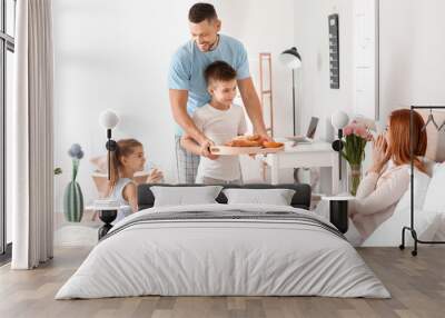 Happy husband with children bringing his wife breakfast in bed Wall mural