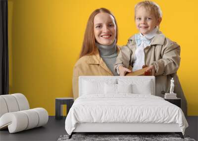 Happy mother and her little son with toy car on yellow background Wall mural