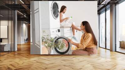 Happy mother with her little daughter doing laundry at home Wall mural