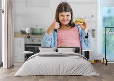 Happy overweight girl eating unhealthy food in kitchen Wall mural