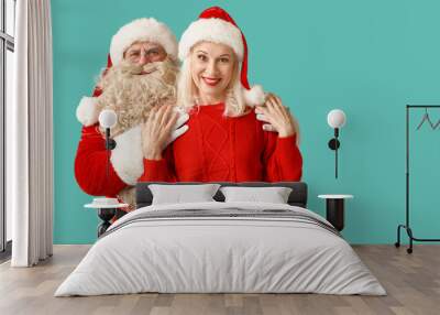 Happy Santa Claus and beautiful mature woman in Christmas hats on blue background Wall mural