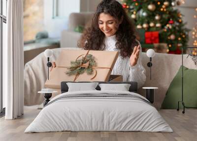 Happy woman opening Christmas gift at home Wall mural