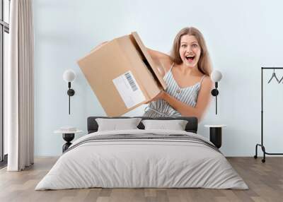 Happy woman with cardboard box on light background Wall mural