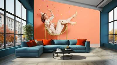 Happy woman with party whistle and glass of champagne near color wall Wall mural