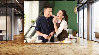 Happy young couple cooking together in kitchen Wall mural