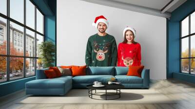 Happy young couple in Christmas clothes on light background Wall mural