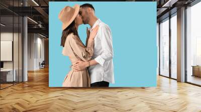 Happy young couple kissing on blue background Wall mural