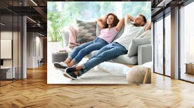 Happy young couple relaxing on sofa at home Wall mural