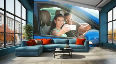 Happy young couple taking selfie in car Wall mural