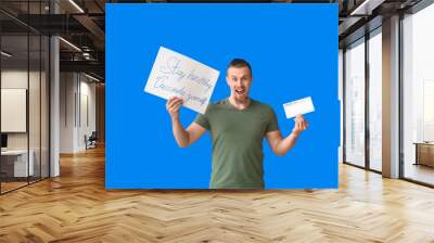 Happy young man holding poster with text STAY HEALTHY - VACCINATE YOURSELF and International Certificate of Vaccination on color background Wall mural