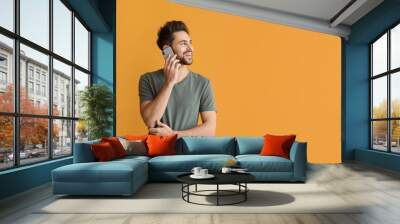 Happy young man talking by mobile phone on color background Wall mural