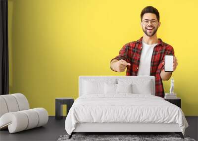 Happy young man with mobile phone on color background Wall mural