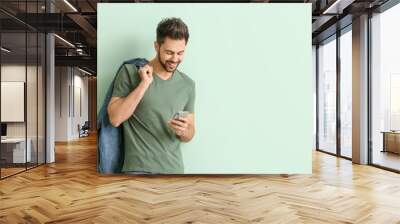 Happy young man with mobile phone on color background Wall mural