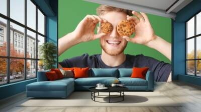 Happy young man with tasty cookies on color background Wall mural